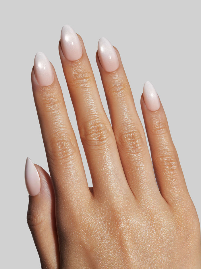 Close-up of a hand with light pink press-on nails on a neutral background