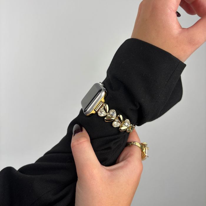 Gold Sparkle Petal Apple Watch strap by Coconut Lane, adjusted on a wrist over a black long-sleeve top.