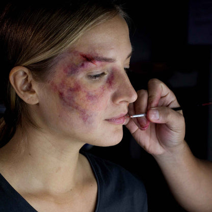 Artist applying realistic bruise and injury SFX makeup on model