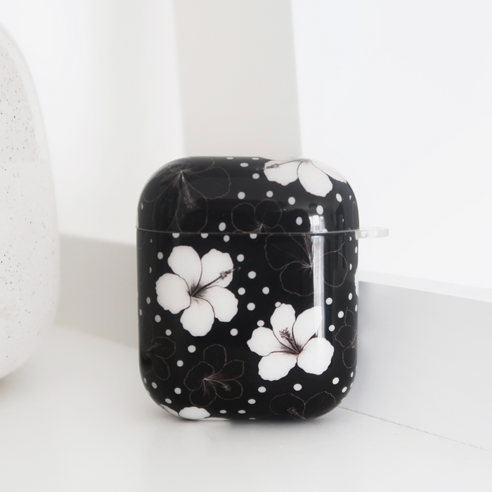 Black floral Coconut Lane AirPods case with white dots, displayed on a white surface.