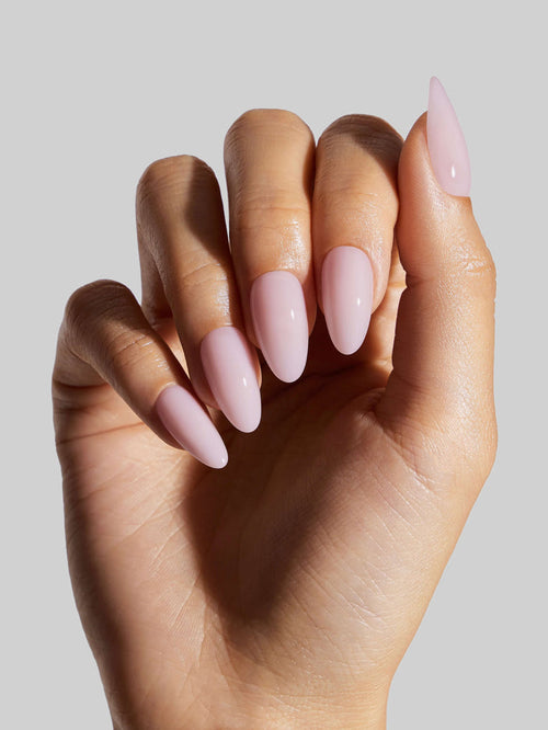 Hand with pink ballerina press-on nails on a neutral background