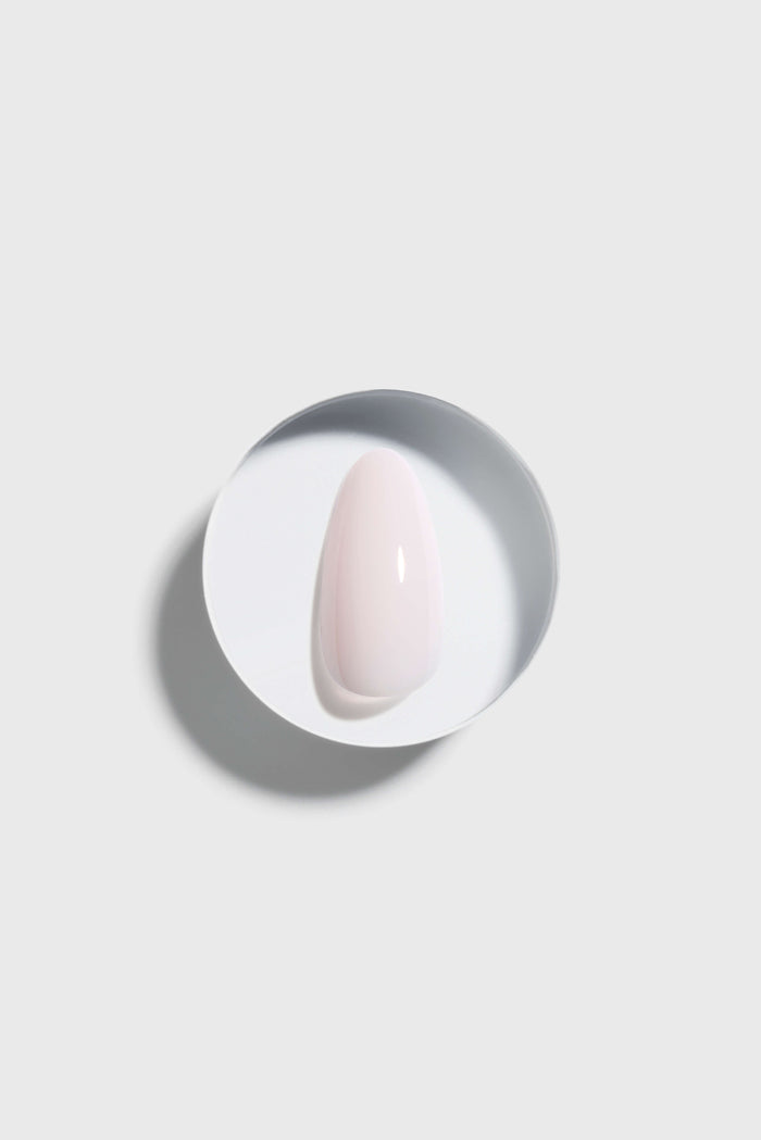 Pink press-on nail on a white plate with a gray rim against a light gray background