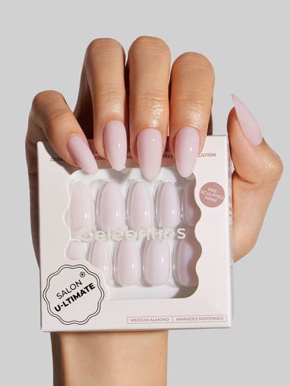 Hand holding a box of press-on nails with a neutral background