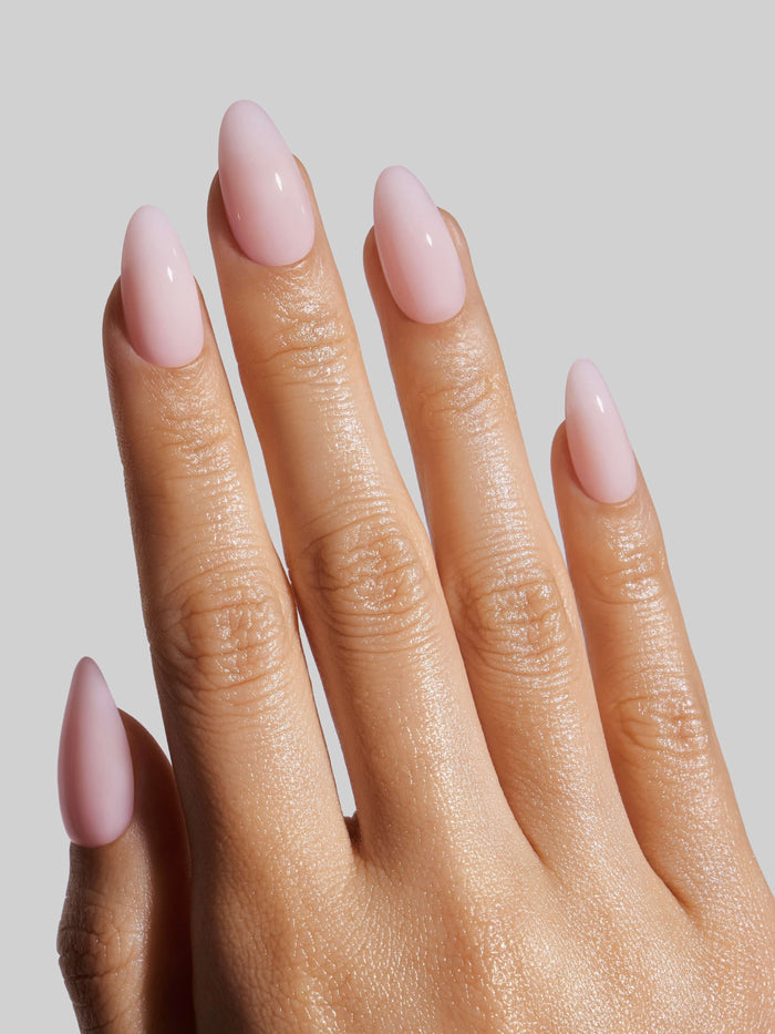 Hand with pink press-on nails on a plain background