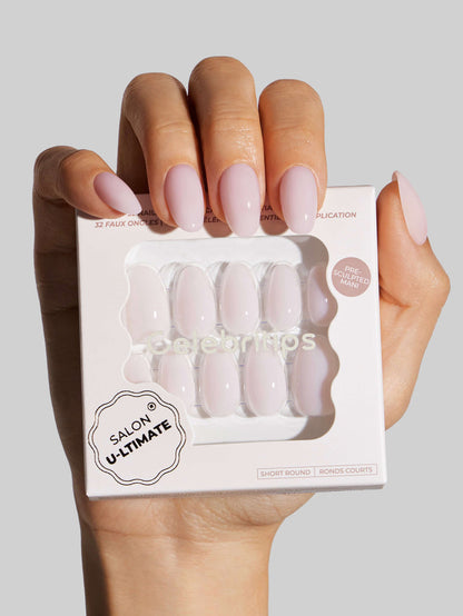 Hand holding a box of 'Salon Ultimate' nail products against a gray background