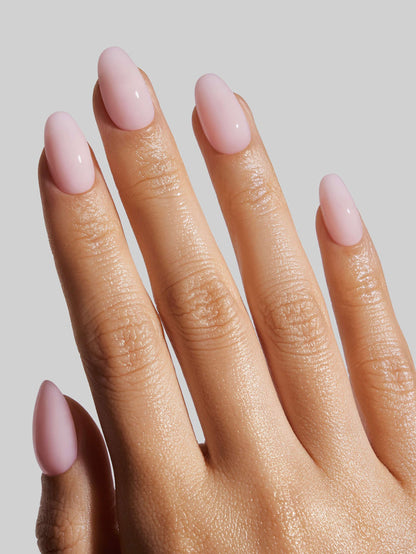 Hand with pink ballerina press-on nails on a plain background