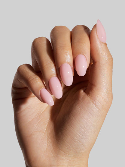 Hand with pink nail polish on a plain background