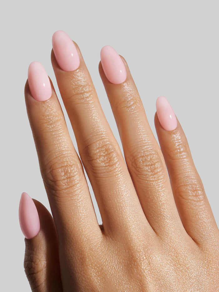 Hand with pink nail polish on a plain background