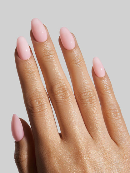 Hand with pink nail polish on a plain background