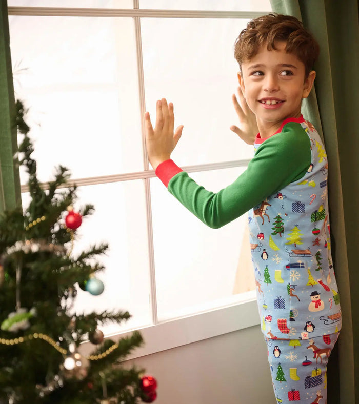Boy wearing Hatley Blue Christmas pajamas near a holiday tree for cozy winter mornings.