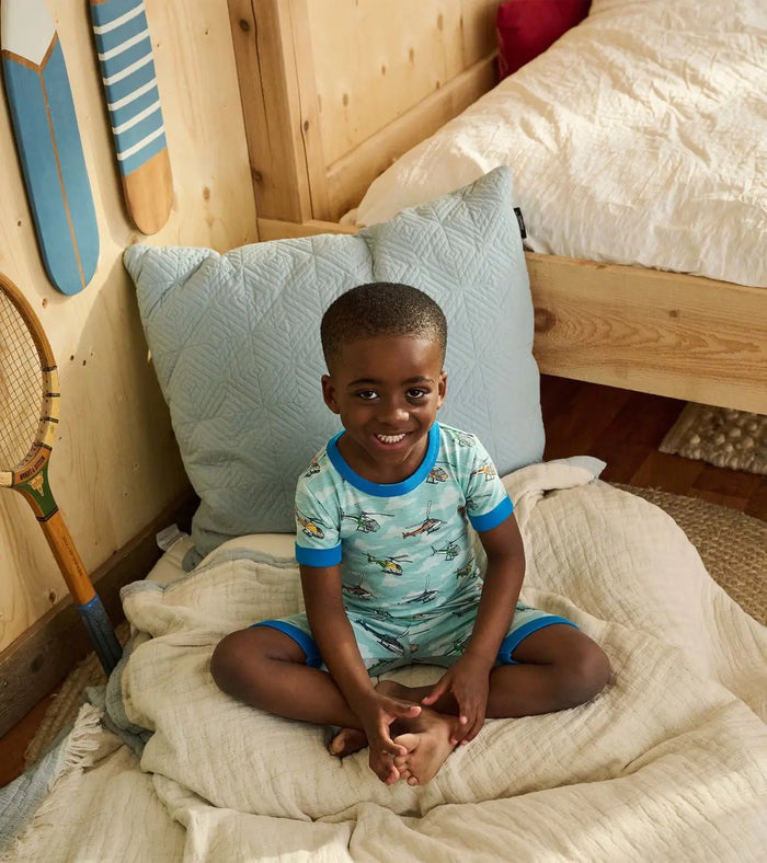 Boy sitting in Hatley Helicopters cotton short pajama set for bedtime and lounging.