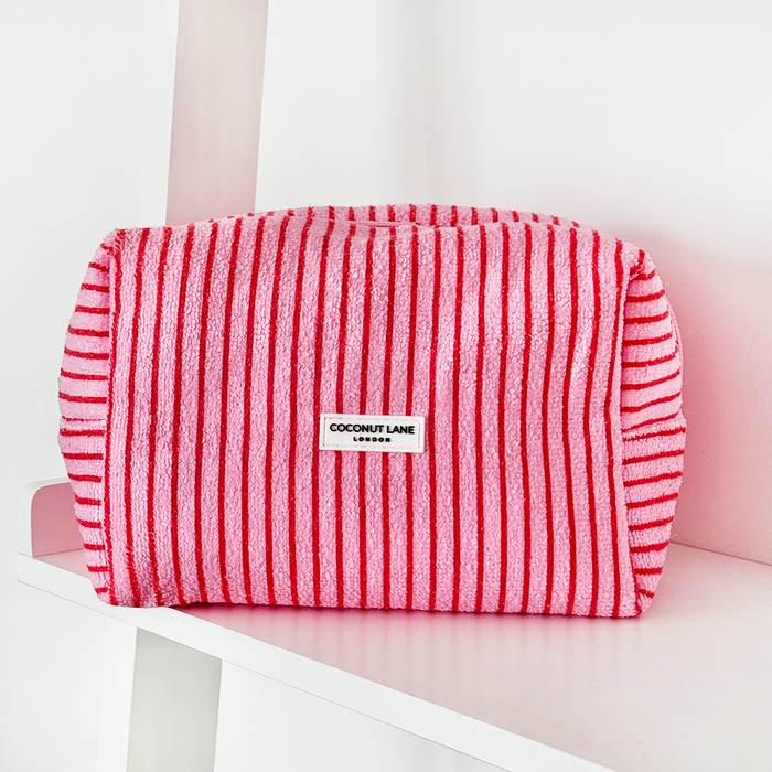 Cherry Stripes towel, makeup bag, and scrunchie set with red and white stripes, displayed on a white shelf.