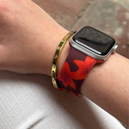 Wrist wearing Coconut Lane Cinnamon Lily Apple Watch strap with gold bracelet on white fabric.