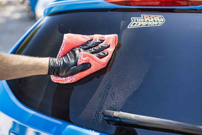 Citrus Twist towel wiping off the window of a blue car