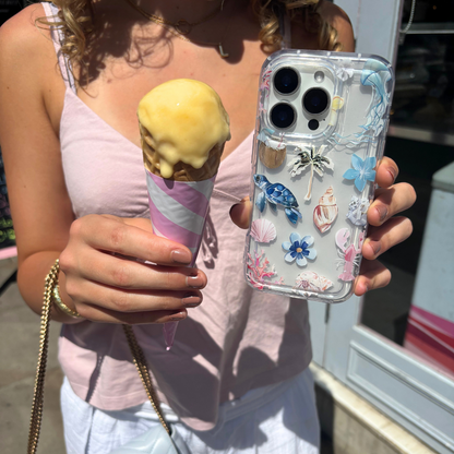 Hand holding a melting ice cream and an iPhone in a clear Coconut Lane phone case with Beach Girl Summer design.