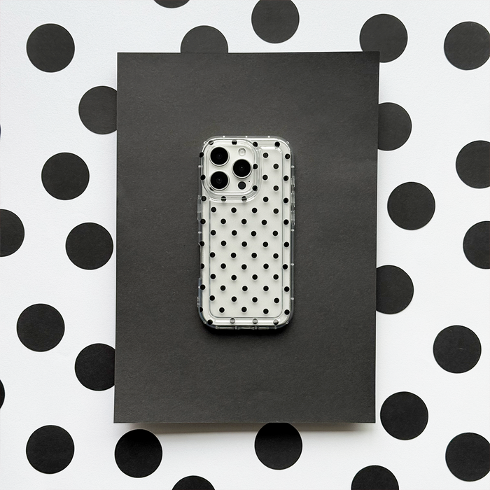 Clear phone case with black polka dots by Coconut Lane, displayed on a matching black and white polka dot background.