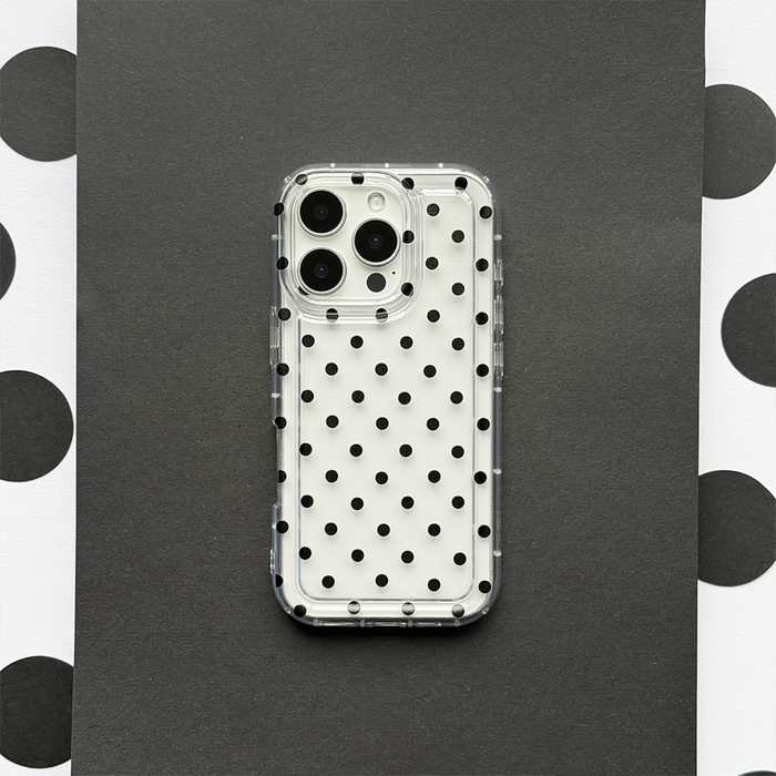 Clear phone case with black polka dots, fitted on a smartphone, displayed on black and white polka dot paper.