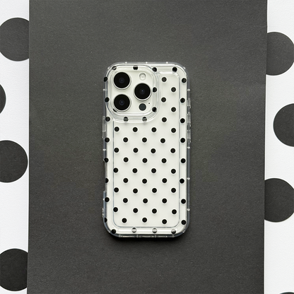 Clear phone case with black polka dots, fitted on a smartphone, displayed on black and white polka dot paper.