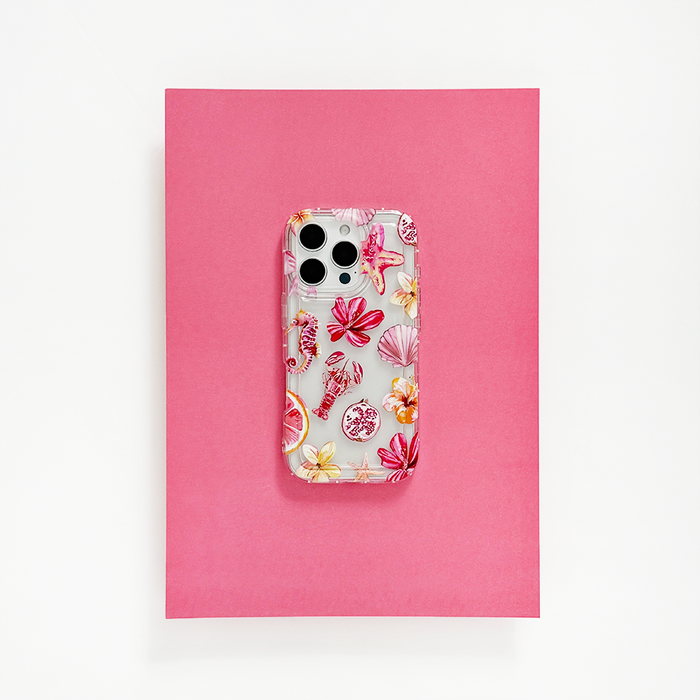 Clear Coconut Lane Rosé Coast phone case on a smartphone, resting on a bright pink sheet with white background.