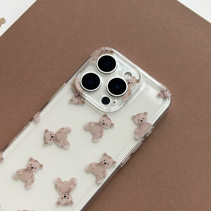 Clear phone case with light brown teddy bear pattern, displayed on a brown surface.