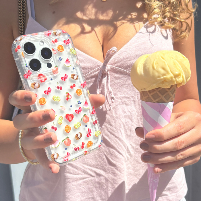 Woman holding a clear Coconut Lane phone case with a colorful Tutti Fruiti pattern and a vanilla ice cream in pink waffle wrap.