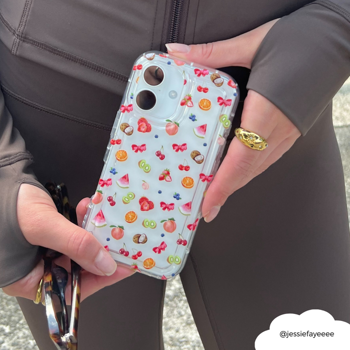 Hand holding a phone with Coconut Lane clear Tutti Fruiti case and a pair of sunglasses.