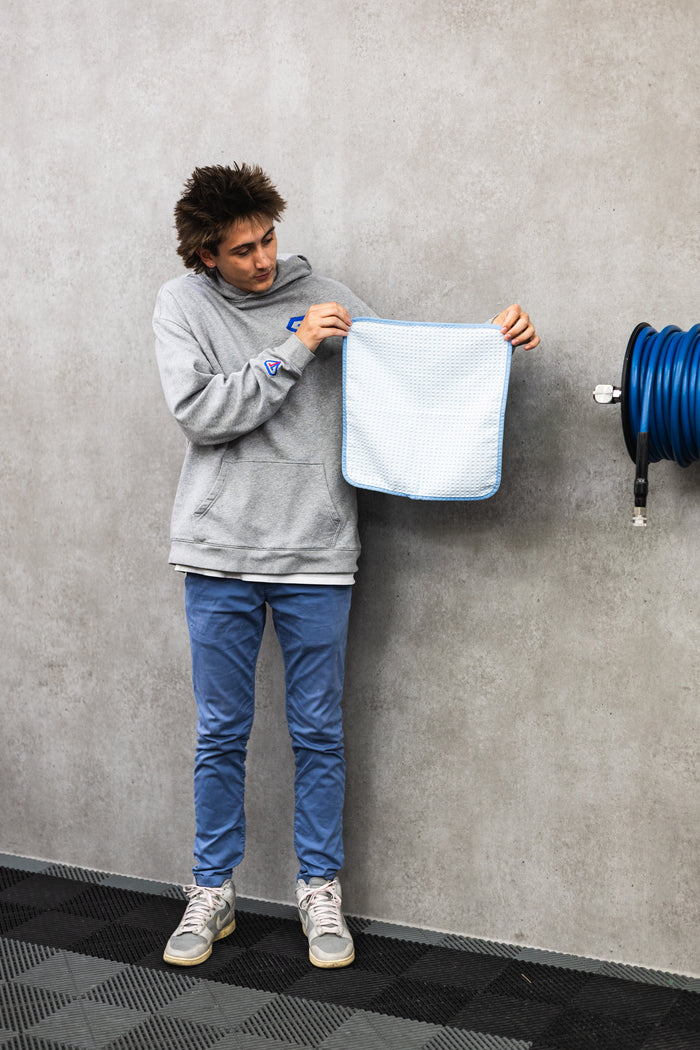 Person holding a white 16x16 dry me a river microfiber towel.