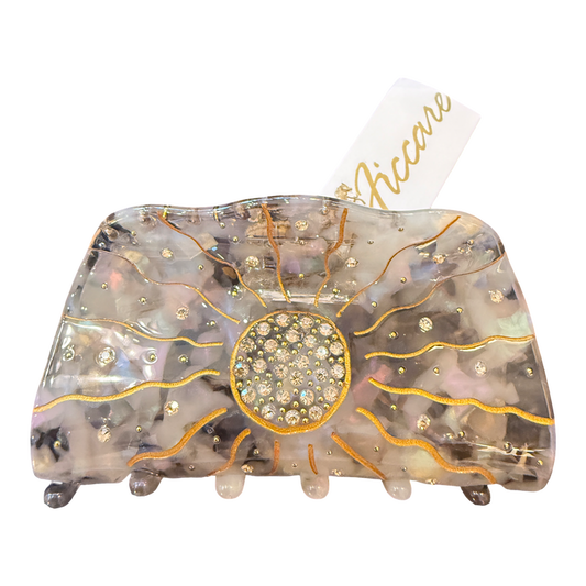 A large hair claw clip by Accare, featuring a translucent iridescent resin body with gold glitter sunburst lines, a central round rhinestone cluster, and small rhinestone accents, shown on a white background with a white paper tag.