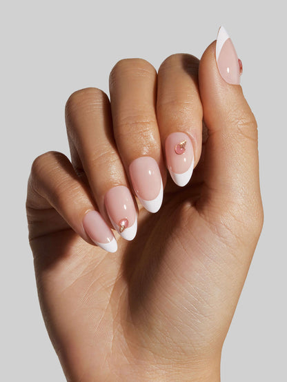 Hand with pink and white press-on nails on a plain background
