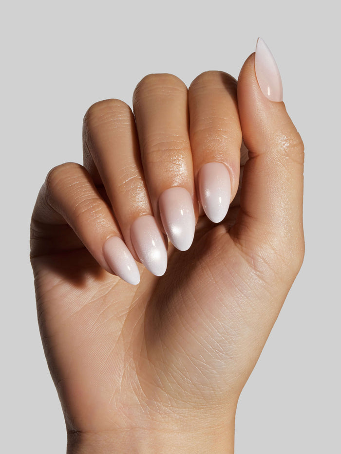 Hand with light pink press-on nails on a neutral background