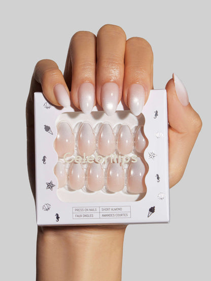Hand holding a package of Glow at Classic Tips press-on nails with a neutral background