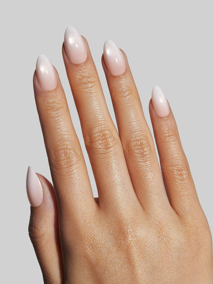 Close-up of a hand with light pink press-on nails on a neutral background