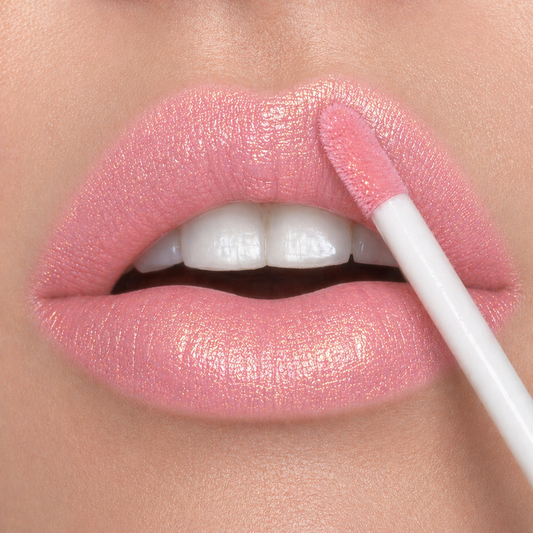 Lip close-up of a woman applying Runway Rogue Long Wear Liquid Lipstick in the shade 'Go See' a soft baby pink with gold shimmer