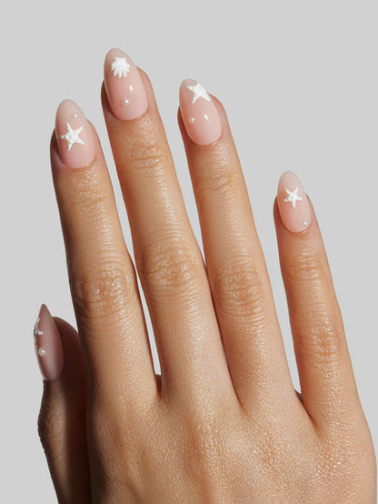 Hand with pink press-on nails featuring star designs on a plain background