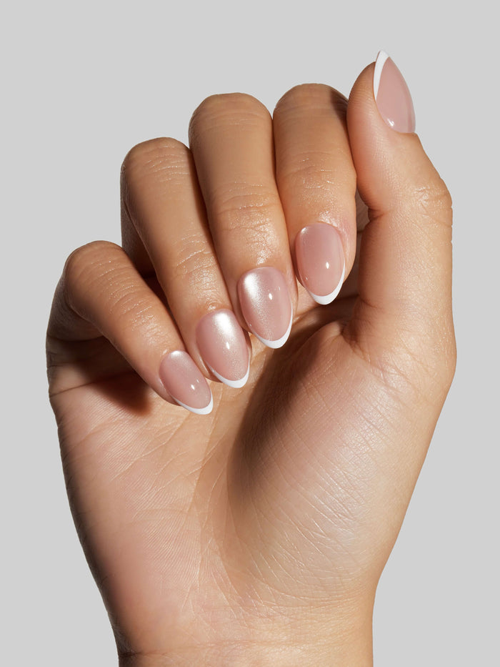 Close-up of a hand with neutral press-on nails with a white tip on a neutral background