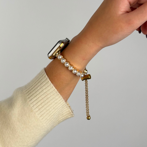 Gold and pearl Apple Watch strap on a wrist, shown against a plain light background.
