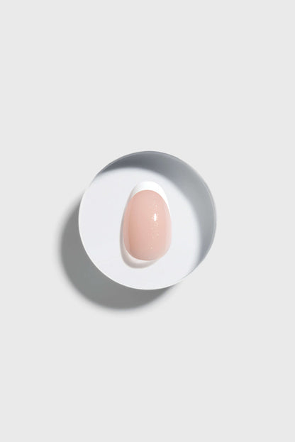 A French Tip press-on nail on a white plate with a gray background