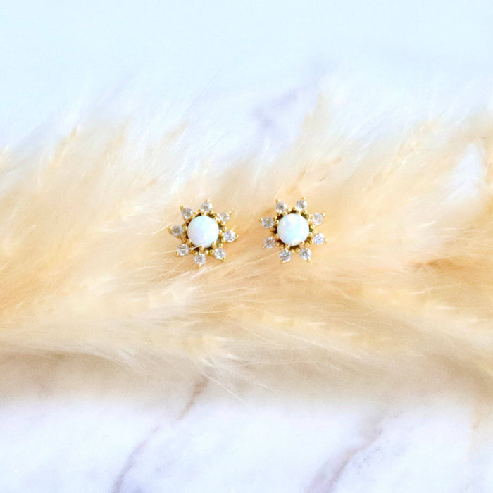 Gold earrings with white stones on a fur surface