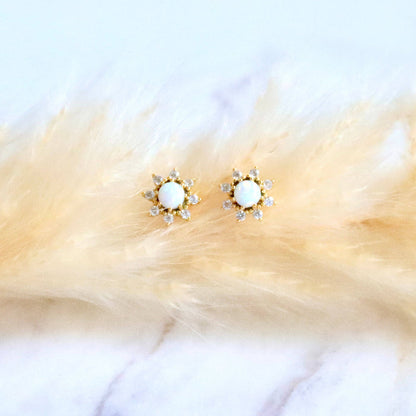 Gold earrings with white stones on a fur surface