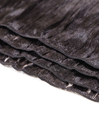 Close-up of several layers of black straight synthetic hair extensions, featuring visible stitching along the top edge on a white surface.