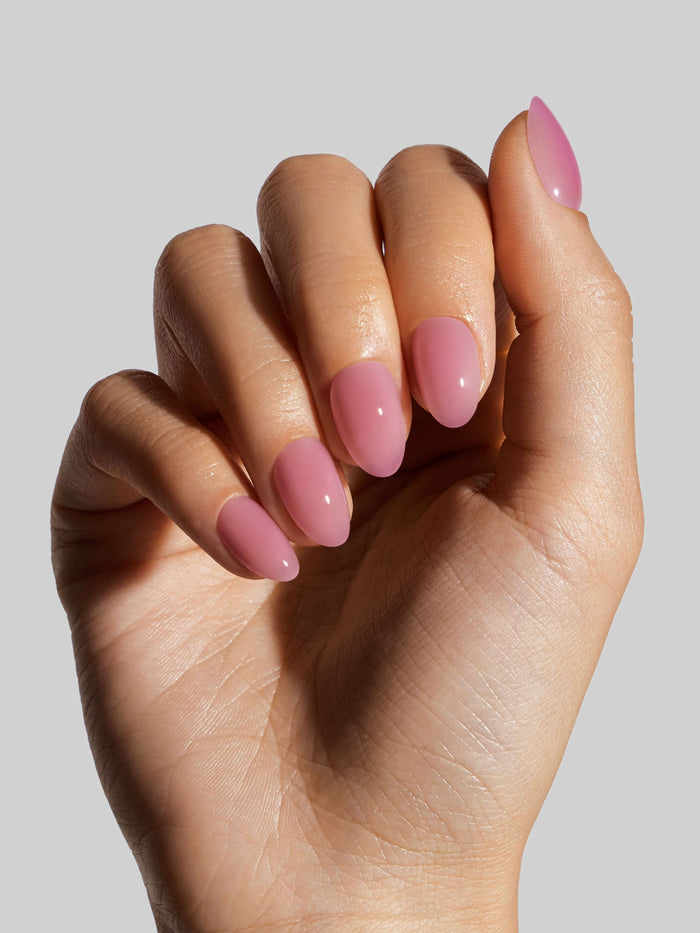 Hand with pink press-on nails on a plain background