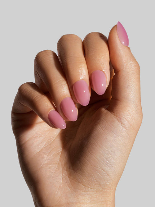 Hand with pink press-on nails on a plain background