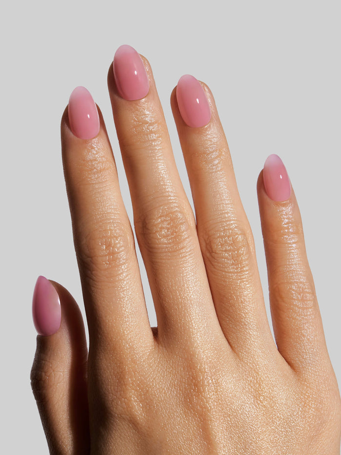 Hand with pink press-on nails on a plain background