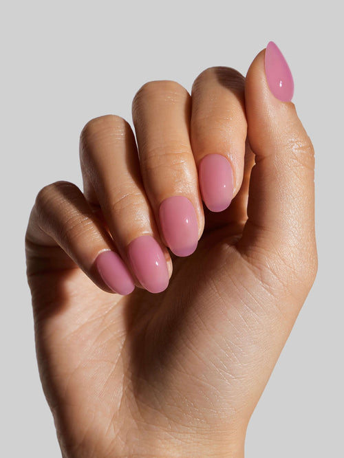 Hand with pink press-on nails on a plain background