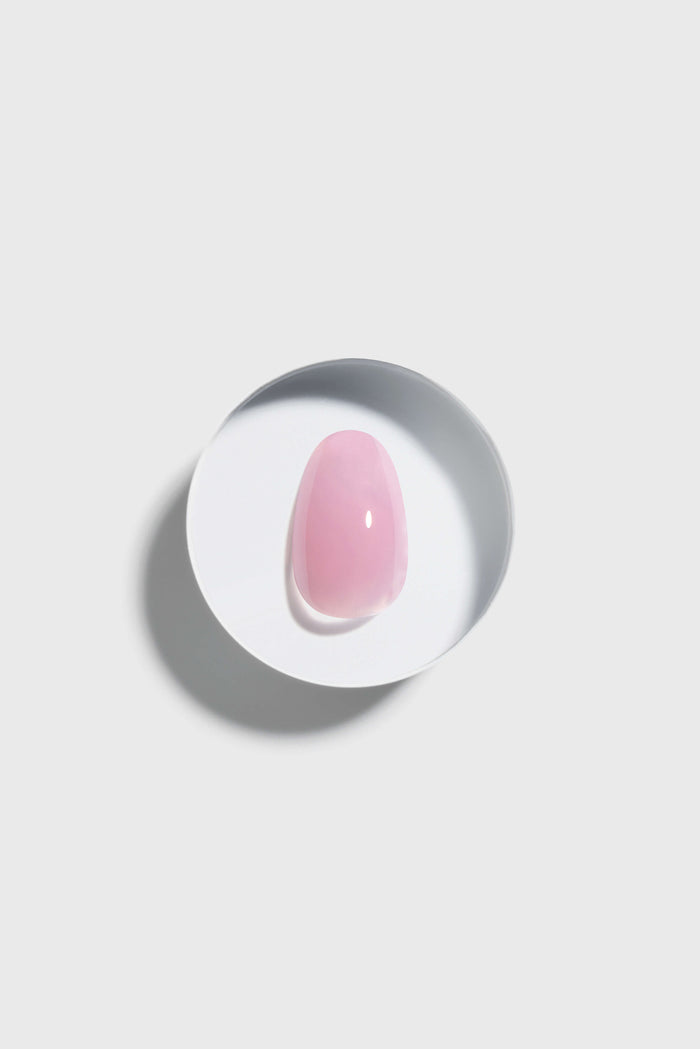 pink press-on nails on a white plate with a gray rim against a light gray background
