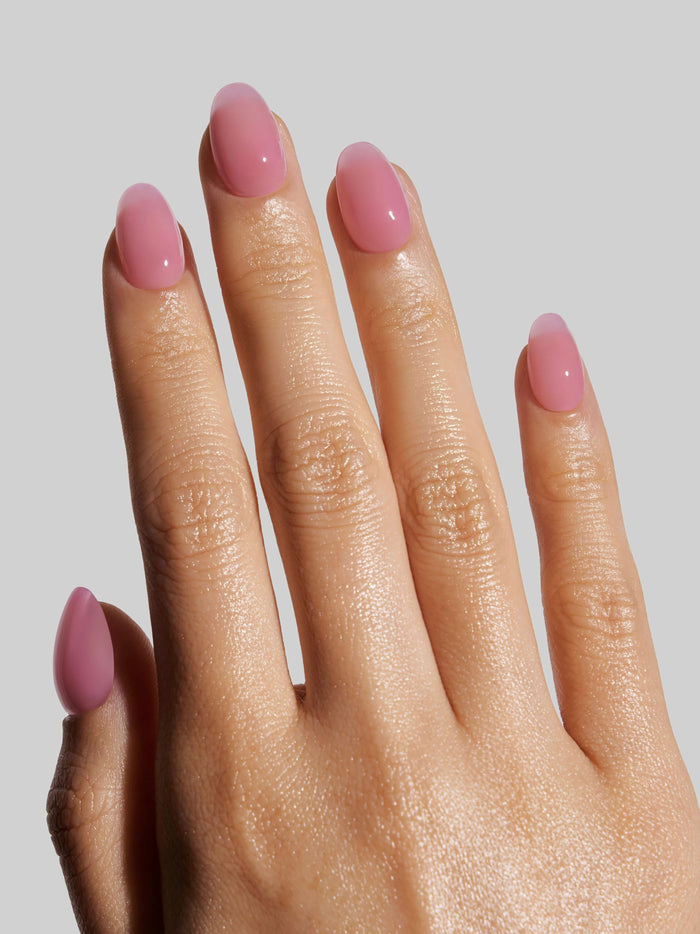 Hand with pink press-on nails on a plain background