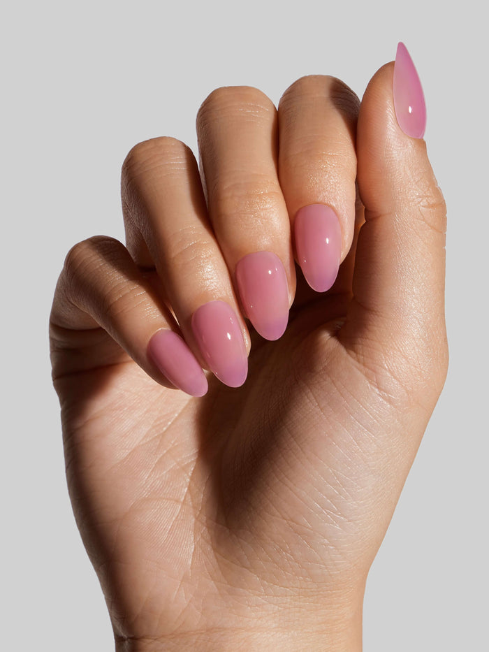 Hand with pink press-on nails on a plain background