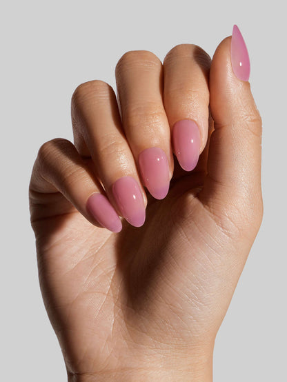 Hand with pink press-on nails on a plain background