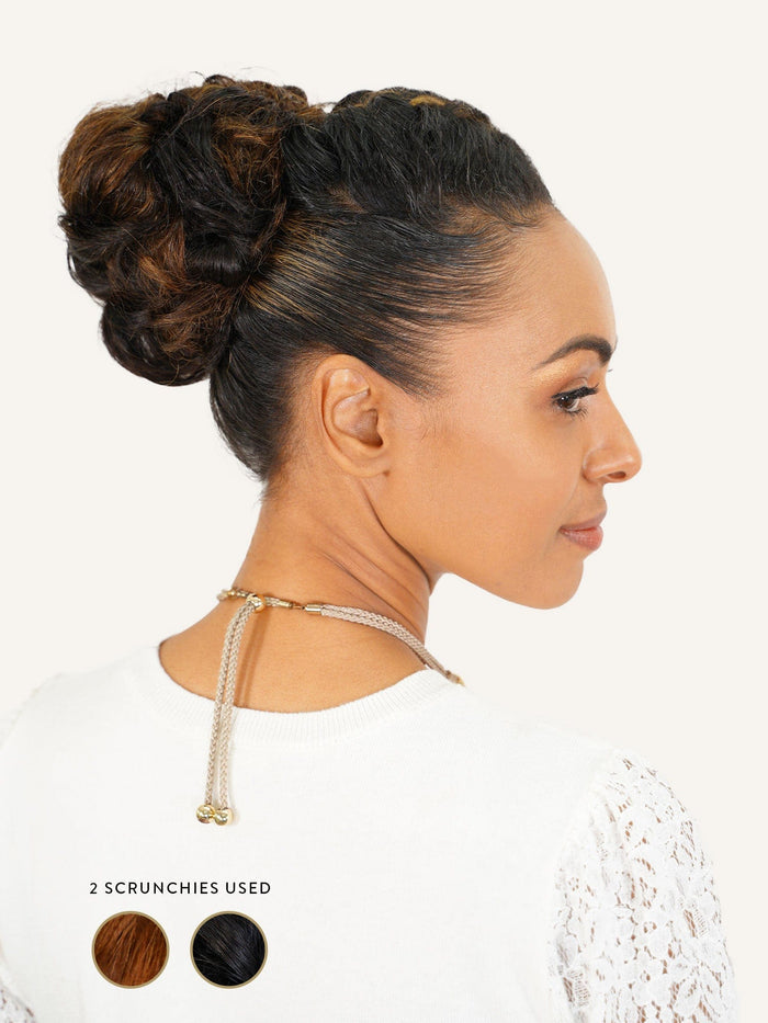 A woman with dark, highlighted hair in a double-bun updo wears a white lace-sleeved top, gold necklace, and colored scrunchies.#color_chocolate-brown-(3)
