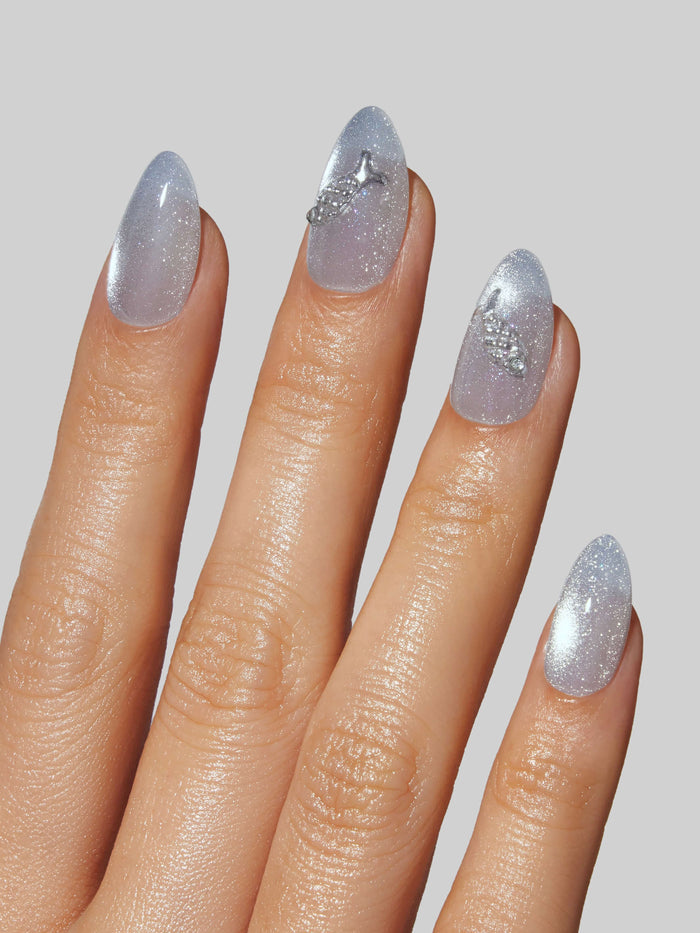 Close-up of a hand with glittery silver press-on nails on a plain background